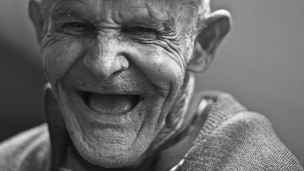 elderly man with a wide smile laughing